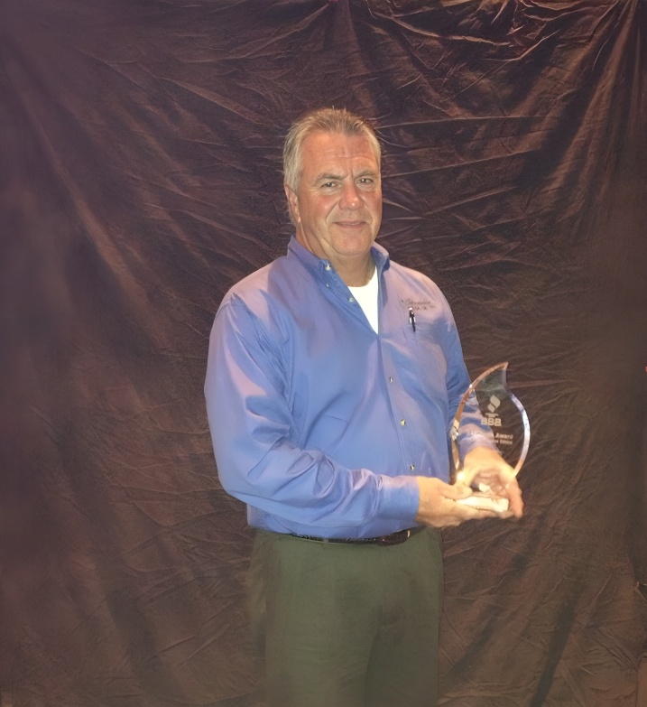 A man holding an award in front of a black background.