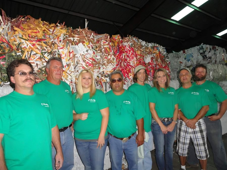 A group of people standing in front of a wall full of garbage.